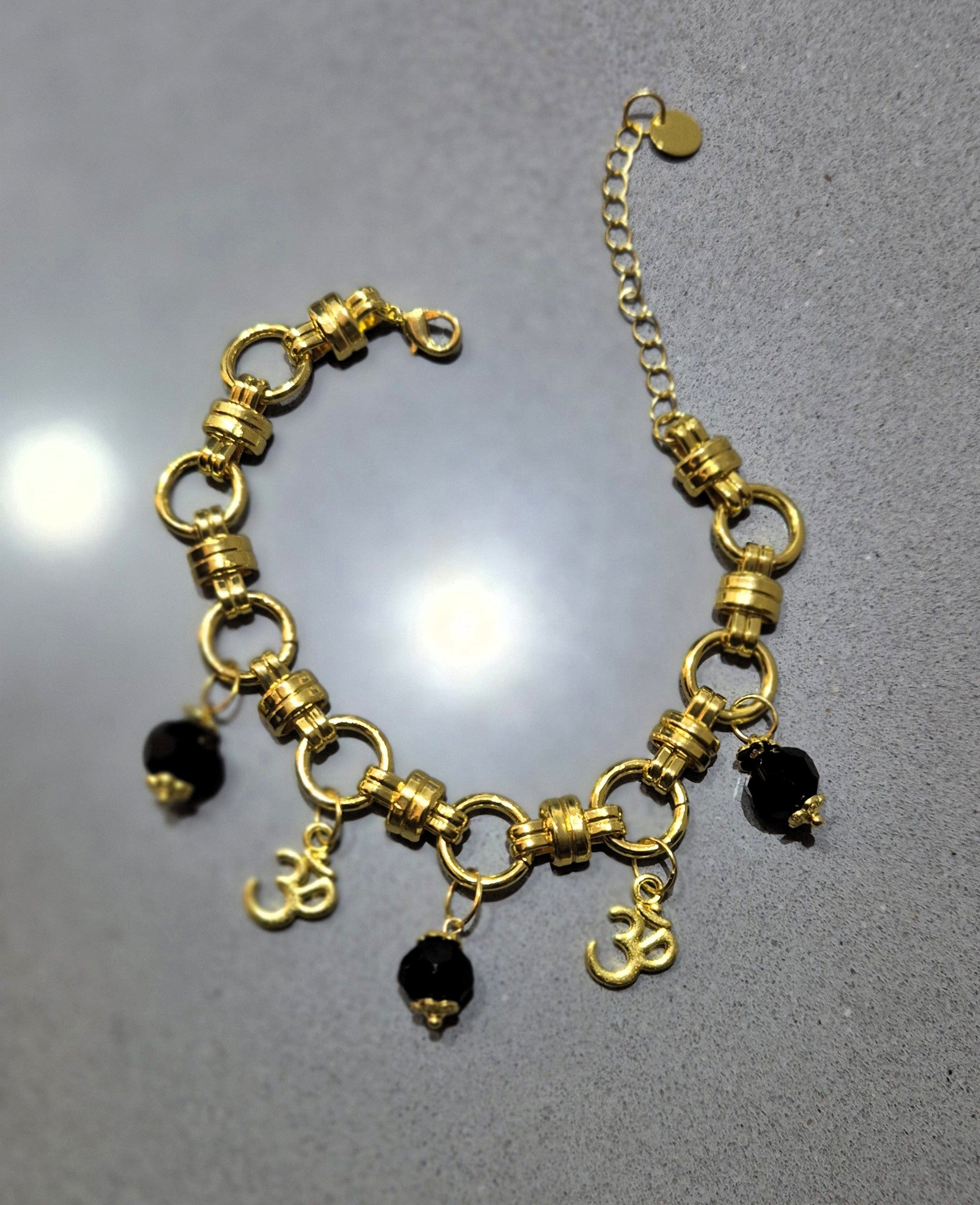 Armband Ogri Serenity – goudkleurig stainless steel met zwarte Ogri Ai kralen & Ohm bedels