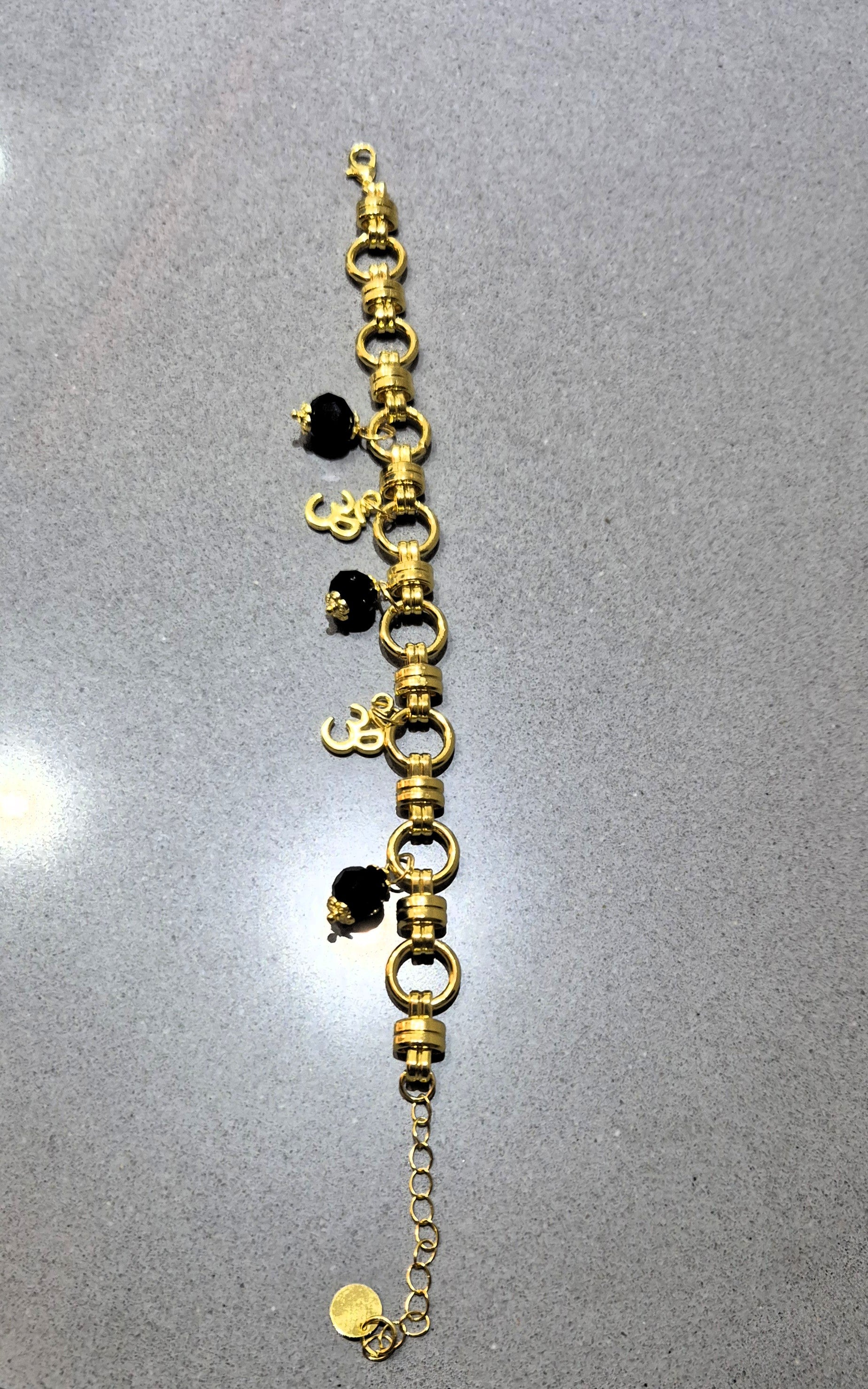 Armband Ogri Serenity – goudkleurig stainless steel met zwarte Ogri Ai kralen & Ohm bedels