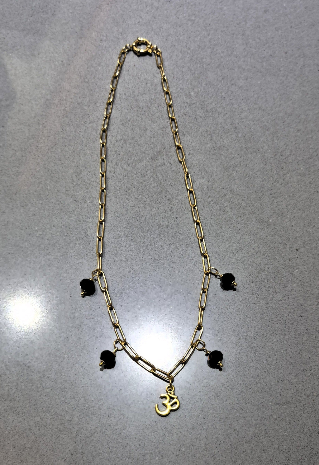 SuRosha Harmony Necklace - Goudkleurig stainless steel ketting met zwarte Ogri Ai kralen & Ohm hanger