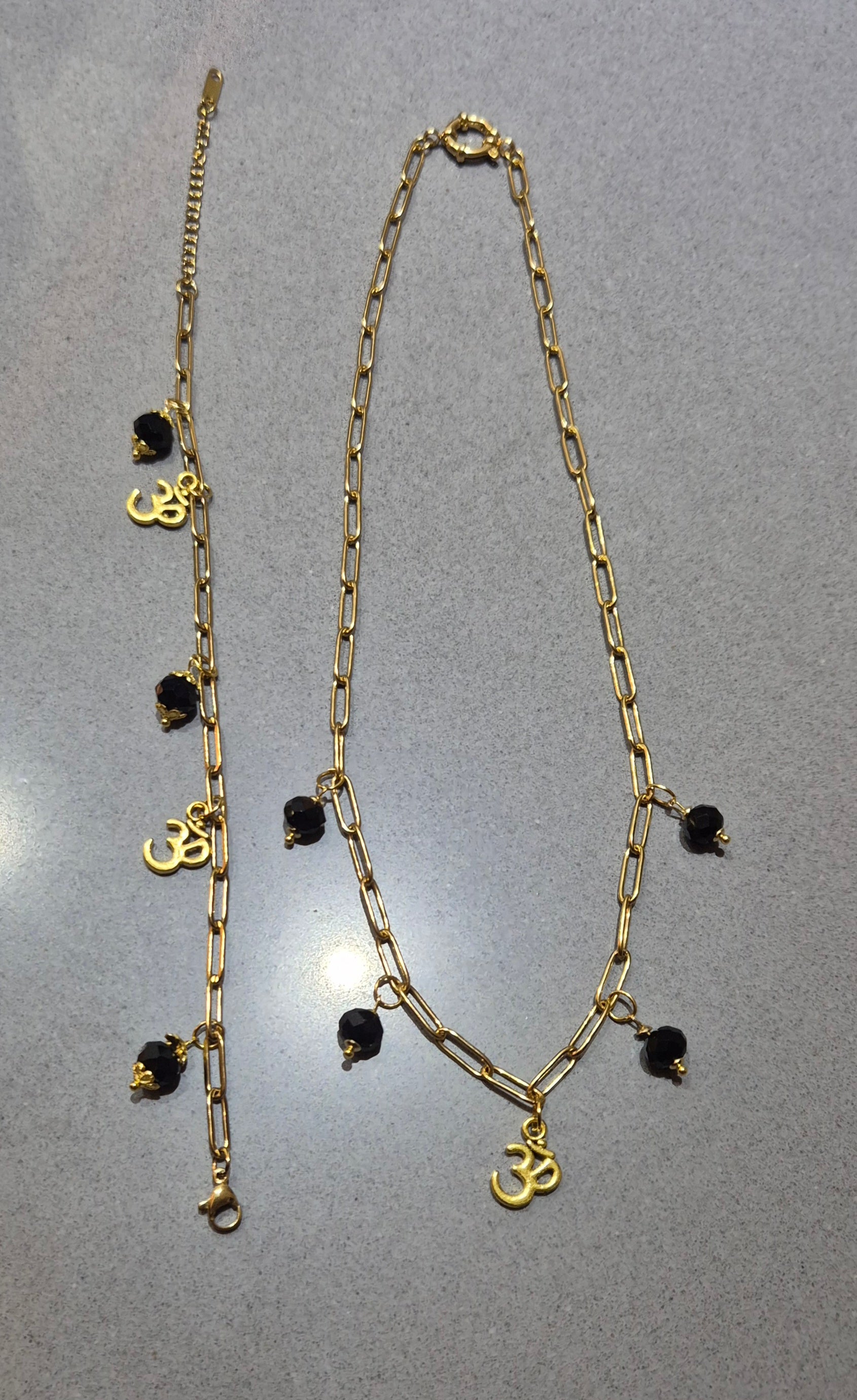 SuRosha Harmony Necklace - Goudkleurig stainless steel ketting met zwarte Ogri Ai kralen & Ohm hanger