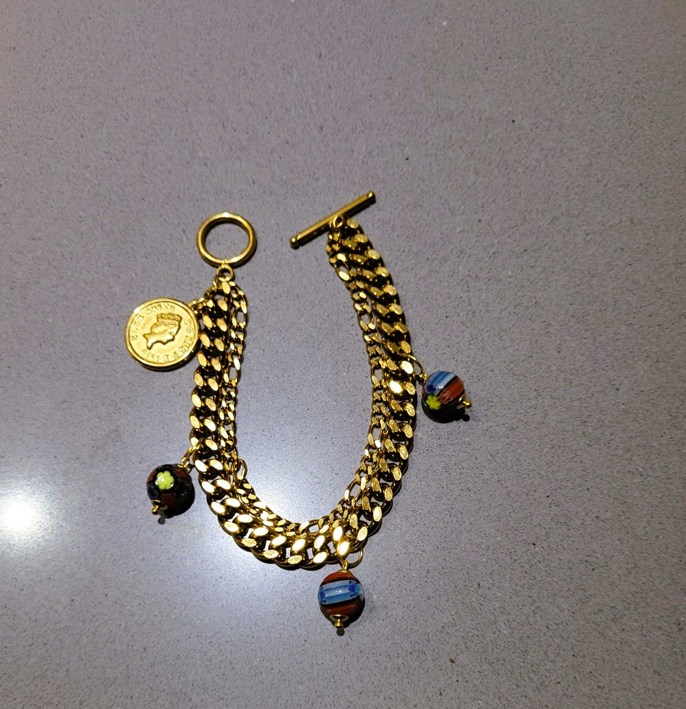 SuRosha Royal Essence – Goudkleurige schakelarmband met A la Kondre kralen & muntbedel