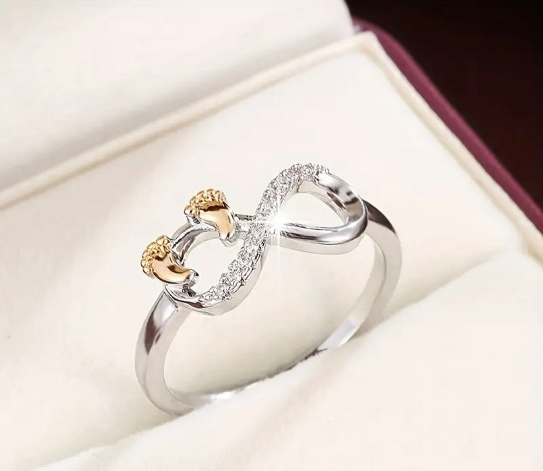 Zilveren infinity-ring met goudkleurige babyvoetjes en zirkonia